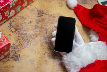 Santa Claus showing using mobile phone on festive background. Closeup shot elderly person with digital gadget, technology copyspace wireless wishlist concept. top side view old adult social post idea