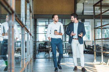 smiling business colleagues having conversation while walking in hall