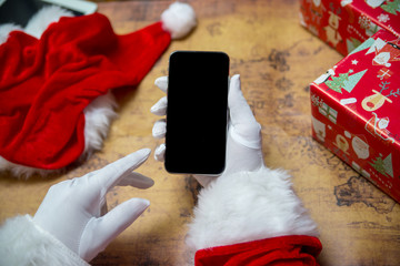Santa Claus showing using mobile phone on festive background. Closeup shot elderly person with digital gadget, technology copyspace wireless wishlist concept. top side view old adult social post idea