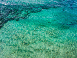 Vista aerea di un mare cristallino con onde e surfisti. Onde che si infrangono sulla spiaggia al tramonto, controluce. Playa De La Canteria. Oceano Atlantico. Orzola, Lanzarote, Isole Canarie. Spagna