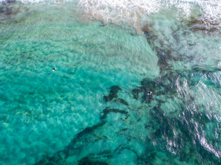 Vista aerea di un mare cristallino con onde e surfisti. Onde che si infrangono sulla spiaggia al tramonto, controluce. Playa De La Canteria. Oceano Atlantico. Orzola, Lanzarote, Isole Canarie. Spagna