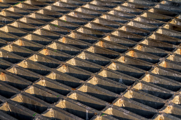 Old metal drain host cover plate textured with sunlight and shadow. Background for pattern and texture design