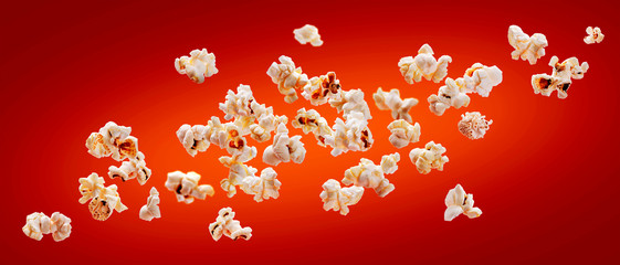 Popcorn isolated on red background. Falling or flying popcorn. Close-up - obrazy, fototapety, plakaty