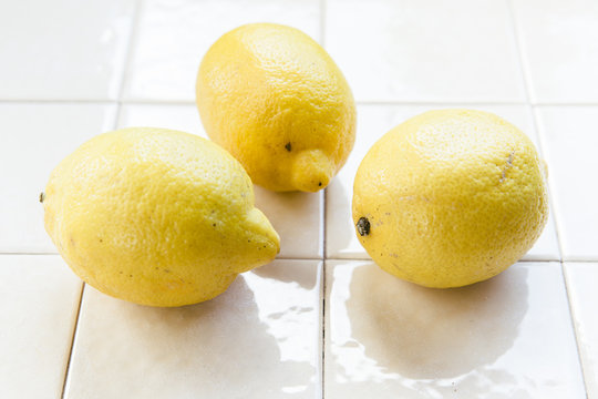 Fresh picked lemons from a local orchard in Southern Italy displayed on white tiles.