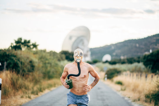 Naked man with tear gas mask on a road.