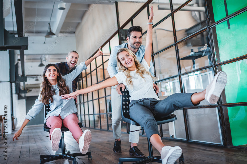 Wall mural happy young coworkers having fun together at workspace