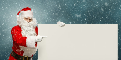 Happy Santa Claus points to a blank banner with to copy space.