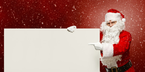 Happy Santa Claus points to a blank banner with to copy space.