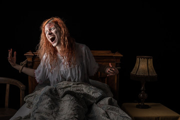 Scary woman possessed by devil in the bed. Exorcism of priest. Woman tied to the bed. - obrazy, fototapety, plakaty