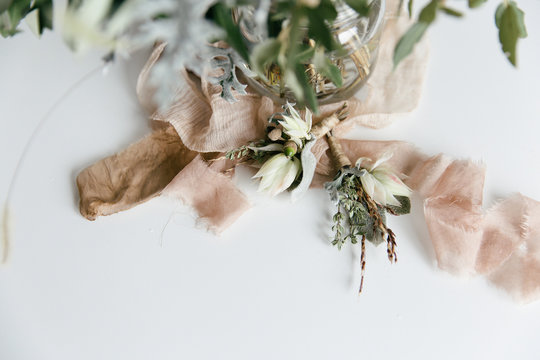 A wedding bouquet in soft green, beige and pink tones in a white neutral setting waiting for the bride on her special day.