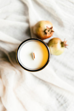 Two pomegranates and a scented candle seen from above.
