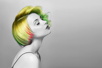 Portrait of a woman with bright colored flying hair, all shades of green. Hair coloring, beautiful lips and makeup. Hair fluttering in the wind. Sexy girl with short  hair. Professional coloring