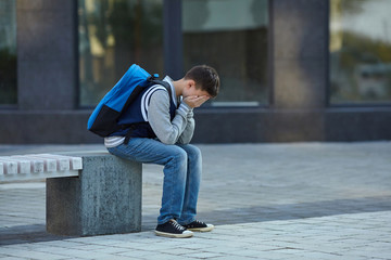 Schoolboy crying in the yard of the school