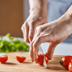 Hands girls cut red cherry tomatoes on a wooden board. Step by Step Cooking Healthy Salad