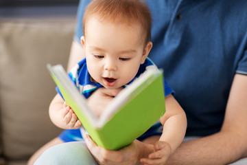 family, parenthood and people concept - close up of happy asian baby boy and father with book at...