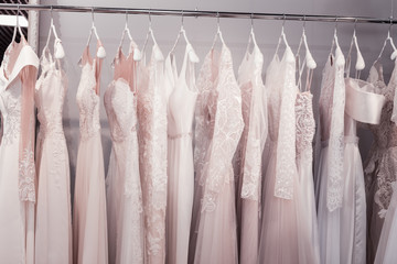 New collection. Close up of beautiful wedding dresses hanging in the shop