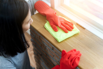 Top side view of young Asian girl wearing in grey shirt and red protective gloves with green rag, cleaning terrace at home.