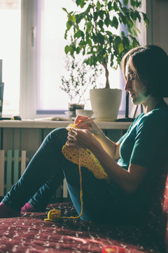 Girl knits crochet at home.