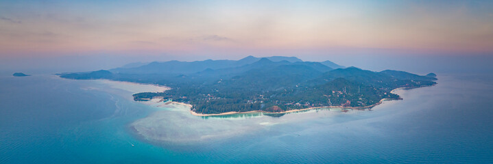 Panorama alone standing island. Sunset aerial drone shot. Ko Pha-ngan. Thailand. Overwhelmed view from above Ko Pha-ngan island and the ocean at the colorful sunset sky. The Kingdom of Thailand