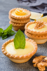 Homemade lemon curd in tartlets with fresh lemon and mint leaves.
