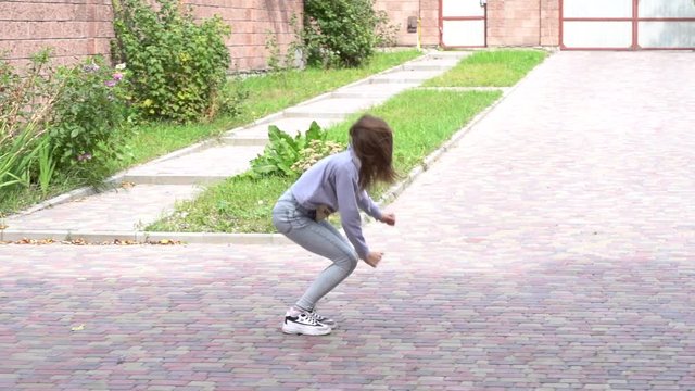 Young flexible girl does cartwheel across frame, outdoors, slow motion. Teenager girl doing acrobatic stunt in yard