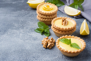 Homemade lemon curd in tartlets with fresh lemon and mint leaves. Copy space