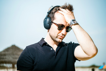 Fashionable man wearing sunglasses enjoying music on his headphones