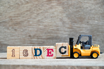 Toy forklift hold block c to complete word 16dec on wood background (Concept for calendar date 16 in month December)
