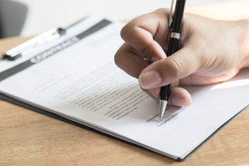 close up hand of businessman signing contract paper