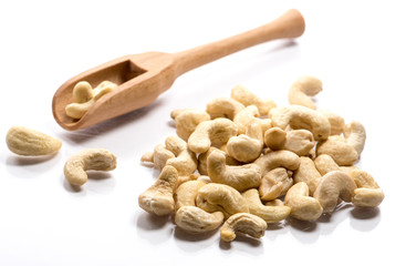 Close-up of pile of raw cashew nuts in a wooden spoon on white background
