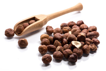 Close-up of pile of raw hazelnuts in a wooden spoon on white background