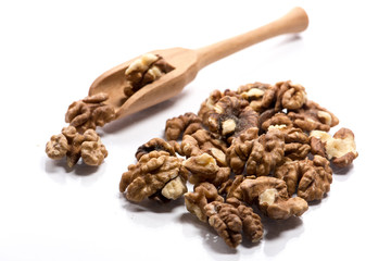 Close-up of pile of raw walnuts in a wooden spoon on white background
