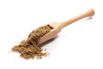 Close-up of pile of ground cumin spice in a wooden spoon on white background