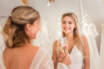 To us. Positive joyful women cheering with glasses with champagne while having a celebration