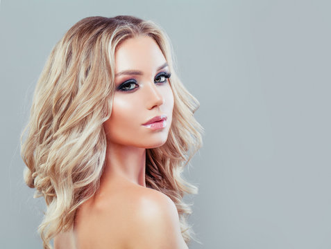 Perfect young woman with blonde curly hairstyle and makeup on blue background