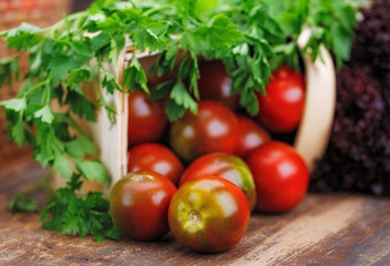 On a wooden table lies basket with tomato, lettuce