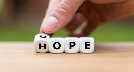 Hand is turning a dice as symbol to have hope instead of dope