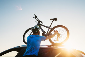 Mountain biker man takes of his bike from the car roof