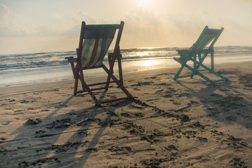silla de playa en amanecer son la luz del sol junto a la arena