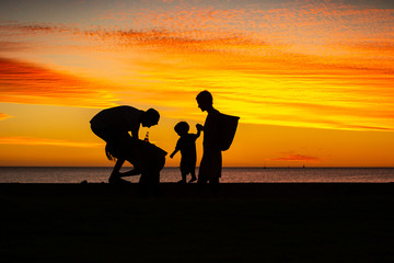 Fototapeta na wymiar silhouettes of a family with a baby at the beach at sunset