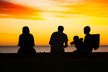 silhouettes of a family with a baby at the beach at sunset