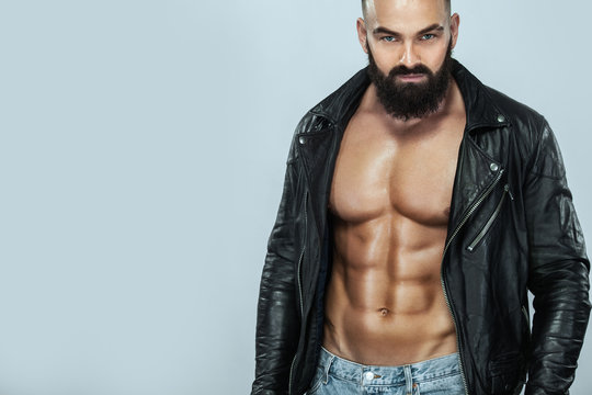 Close-up portrait of a brutal bearded man topless in a leather jacket