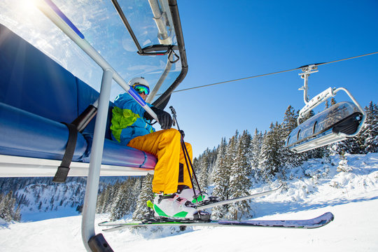 Skier sitting at ski chair lift.