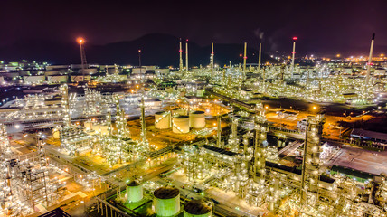 Fototapeta premium Oil storage tank with oil refinery background, Oil refinery plant at night.Aerial view from drone top view