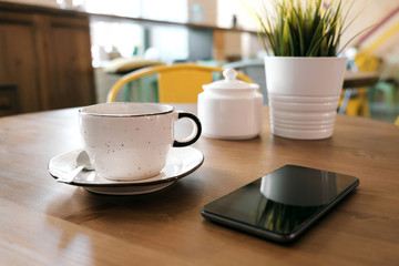 Coffee drink on wooden table with blur cafeteria as background.