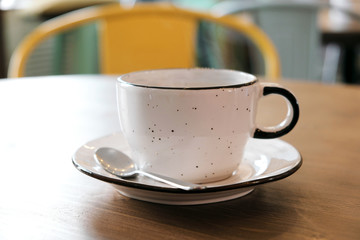 Coffee drink on wooden table with blur cafeteria as background.
