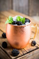 Blackberry moscow mule in copper mug on the rustic background. Selective focus. Shallow depth of field.