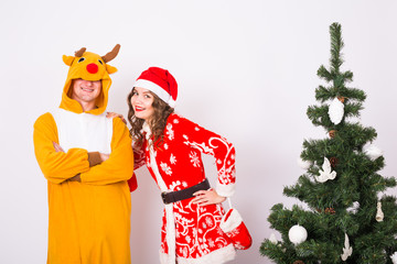 Holiday, Christmas and family concept - Beautiful couple in carnival costumes standing near Christmas tree