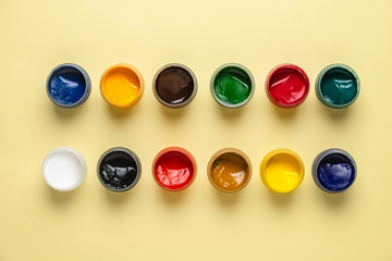 Jars with gouache on a yellow background. White, black, red, blue, green, brown paint.