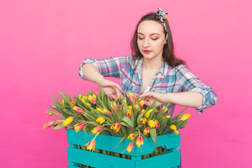 Brunette young woman with bunch of tulips on pink background